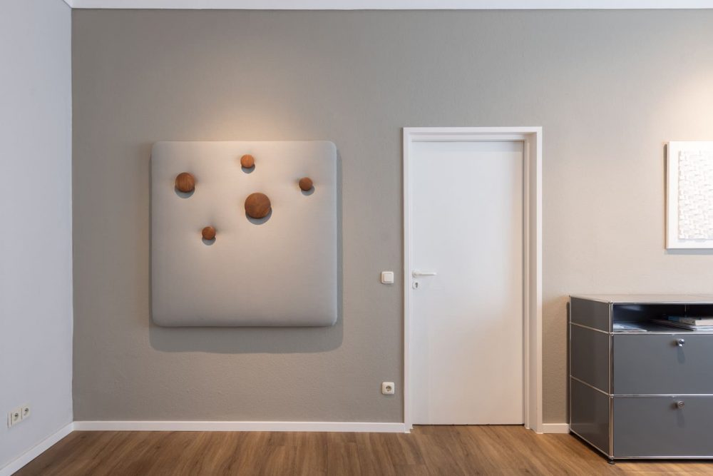 Ausschnitt eines Arztzimmers. Rechts eine weiße Türe. Daneben hängt an der Wand eine Minrath USM Garderobe muuto